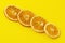 Dehydrated slices of dried oranges diagonally against a bright yellow background. Healthy food concept, vitamins, aromatherapy and