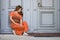 Dejected woman crouching against a historic wooden door waiting