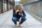 Dejected woman squatting on a bridge