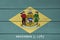 Delaware flag color painted on Fiber cement sheet wall background, yellow diamond shape on green with coat of arms of the state