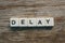 Delay alphabet square on wooden background