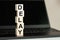 Delay word made with building blocks on the black keyboard. A row of wooden cubes with a word written in black font is located on