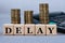 DELAY - word on wooden cubes on the background of coins and calculator