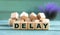 DELAY - word on wooden cubes on a green background with lavender