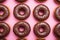 Delectable assortment of chocolate donuts arranged on a vibrant pink background