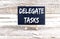 DELEGATE TASKS text on the Miniature chalkboard on wooden background