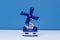 Delft Blue Figurine of blue windmill on a white shelf with a blue background. A souvenir from Holland/Netherlands