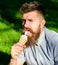 Delicacy concept. Man with long beard eats ice cream, while sits on grass. Bearded man with ice cream cone. Man with