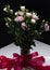 Delicate bouquet of eustoma in a vase with silk ribbon on a dark background. Buds and flowers of prairie gentian. Ve