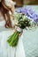 Delicate bride holds a wedding bouquet of violet crocuses in her