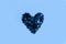 Delicate glitter star confetti shaped heart on blue background