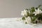 Delicate jasmine flowers on a white table shine against a neutral beige background