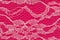 Delicate lace textured material on bright pink knit background