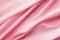 Delicate pink jersey fabric background with swirl creased texture. Sewing fashion clothes making wedding