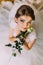 Delicate rose in the hands of young girl dressed white wedding dress