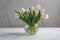 delicate spring tulips in a simple vase on a marble tabletop