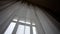 Delicate translucent curtains on a large window in a hotel. Large window with transparent tulle. Large bright window