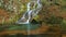 Delicate waterfall in the forest and autumn foliage