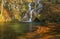 Delicate waterfall in the forest and autumn foliage