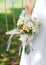 Delicate wedding bouquet of roses, white carnation and white freesia in the bride`s hand