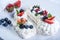 Delicate white meringues with fresh berries on the plate on white background. Dessert Pavlova close-up. Wedding cake.