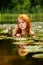 Delicate young sexy red-haired woman enjoys sensually seductive sensual in the water, pond, on a pink water lily flower