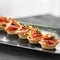 Delicious appetizer with ham, cheese, pepper and tomato in tartlets. Concept of food, restaurant, catering, menu