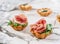 Delicious appetizers in tart with prosciutto and arugula on marble banquet table. Catering food, canape and snacks, close up.