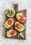 Delicious appetizers with wine - cream cheese, smoked salmon and avocado sandwiches and olives on a wooden board.