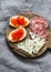 Delicious appetizers for wine - smoked sausage, red caviar cream cheese sandwiches, blue cheese on a wooden chopping board on a gr