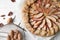 Delicious apple galette and pecans on white wooden table, flat lay