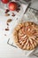 Delicious apple galette and pecans on white wooden table, flat lay