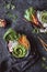 Delicious asian bowls with rice noodles, vegetables and sesame seeds on black background. Top view