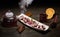 Delicious Asian dessert in long white plate with teapot, orange, berries and spices. Asian menu. Dark wooden background.