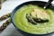Delicious asparagus soup in bowl on white table, closeup