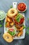 Delicious Bagel Pork sandwiches with vegetable and Tzatziki Sauce and Fries on white board.