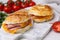 Delicious bagels with ham and cheese on white table, closeup. Space for text