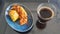Delicious banana cheese cake pastry and pisang bolen on the blue plate with a cup of black coffee
