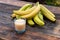 delicious bananas and juice in glass containing lots of vitamin c are good to eat on a brown wooden background