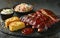 Delicious BBQ ribs served with coleslaw, cornbread, and sauces on a rustic table setting.