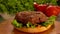 Delicious beef cutlet is falling onto the hamburger bun with green salad