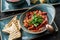 Delicious beetroot soup in bowl, solyanka with meats served with croutons over a dark background, close up view. Concept of