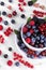 Delicious berries in a bowl, currants, blackberries, blueberries, raspberries on a white wooden table. top view