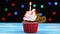 Delicious birthday cupcake with burning candle and number 18 on multicolored blurred lights background