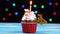 Delicious birthday cupcake with burning candle and number 34 on multicolored blurred lights background