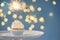 Delicious birthday cupcake with sparkler on stand against blurred lights