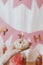 Delicious birthday donut with candle in hand on background of pink garland and decorations in room