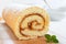 Delicious biscuit roll with apricot jam on a white wooden table. Cutting close-up.