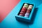 Delicious bitten colorful french macaroons in box on blue and red background