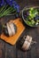 Delicious black burgers, salad and blue flowers on dark wood table